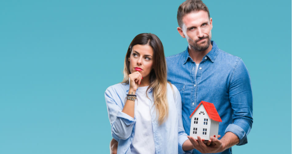 Woman looking questioningly while man holds house model