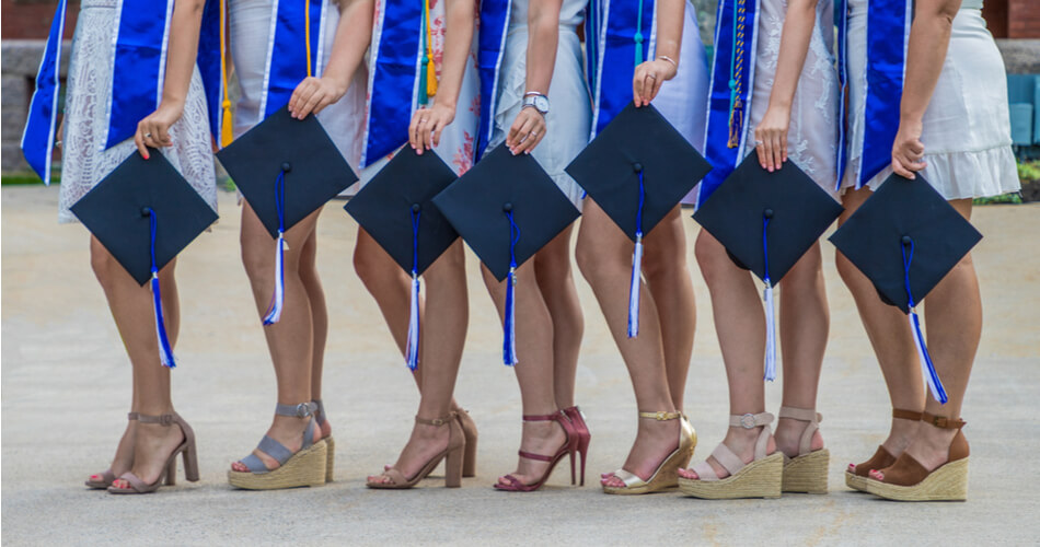Women holding graduation caps in a row