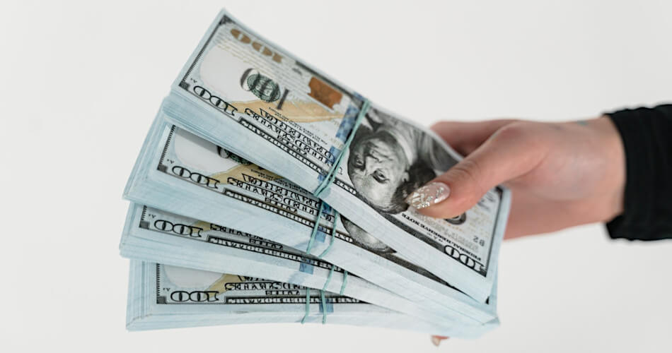 a female hand handing over 4 bundles of 100 dollar bills