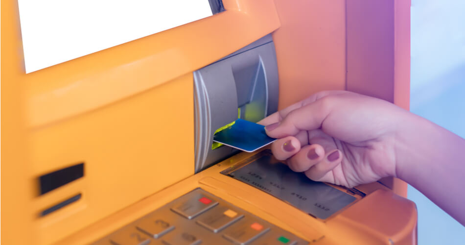 Woman putting bank card into an orange ATM