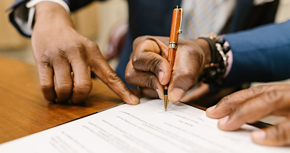 hand of attorney points to where grantor needs to sign a document while setting up a trust and assigning the successor trustee