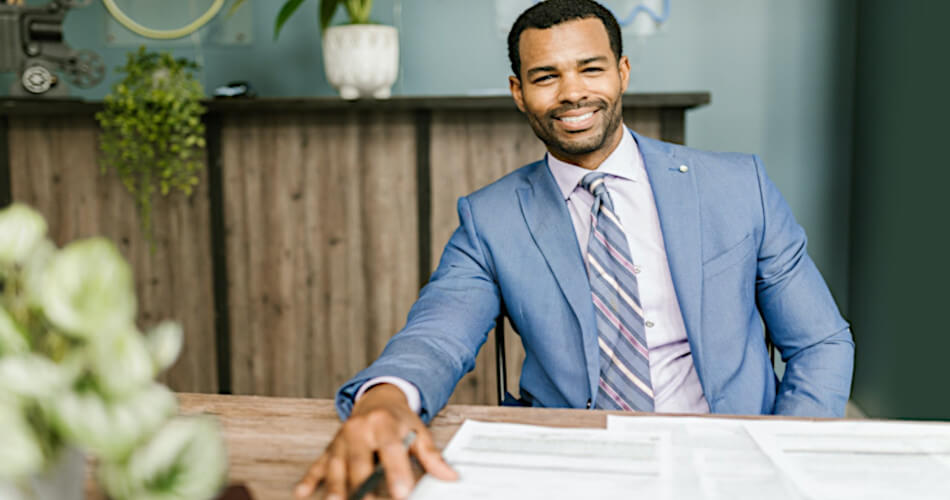 smiling loan originator in business attire with loan documents