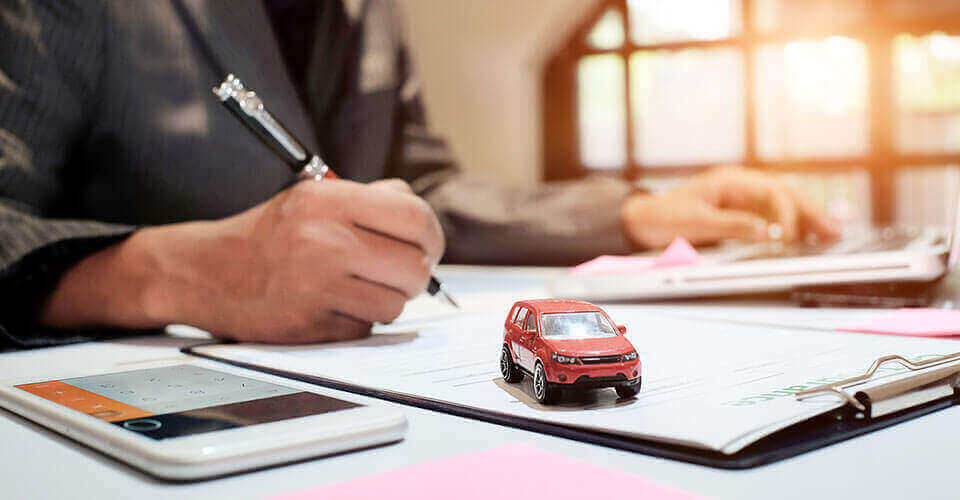 Man signing form with a model car in foreground