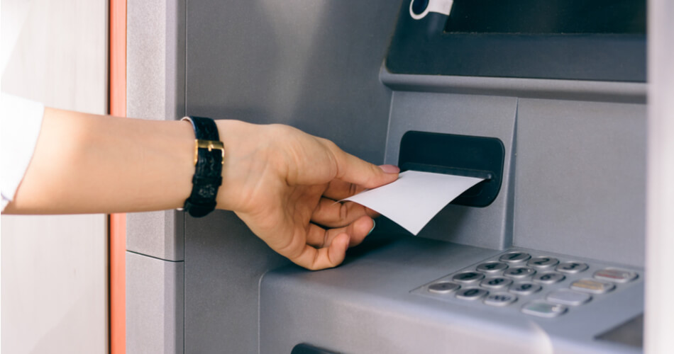 Hand depositing a money order into an ATM