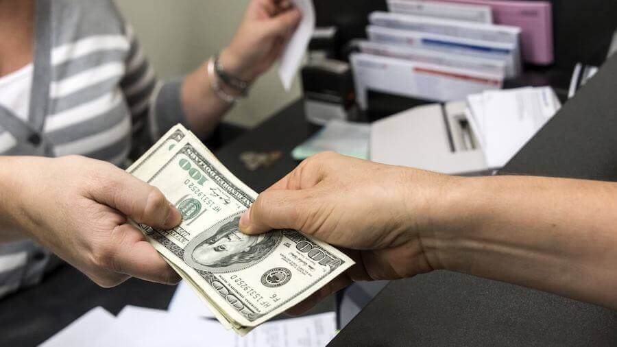 One person handing cash to another person across a desk