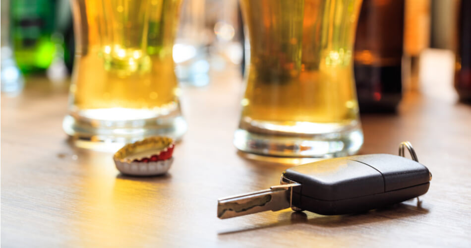 Car keys with glasses of beer and bottle caps in the background