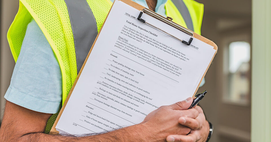 man in yellow vest holds clipboard with home inspective checklist