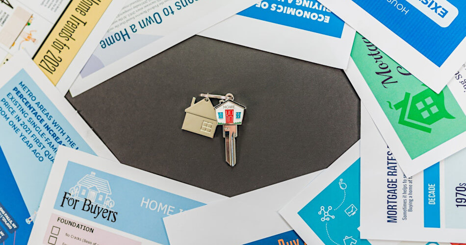 key with house-shaped top on keychain with golden house, surrounded by papers related to home ownership and its benefits