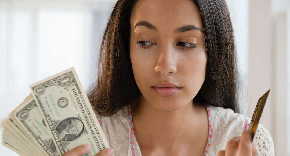 A young woman holding cash and a credit card