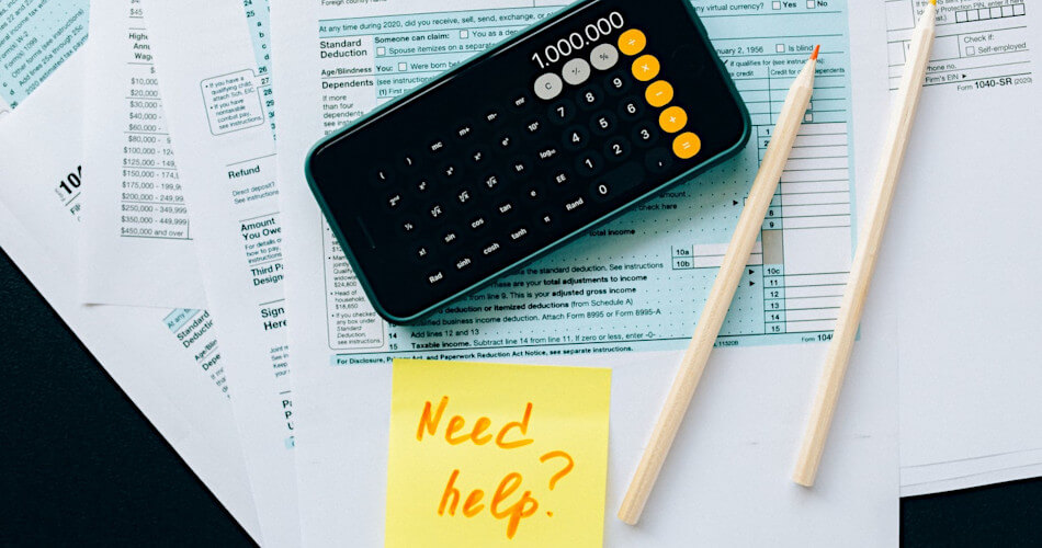 tax forms, calculator, pencils, an post-it note with need help? written on it