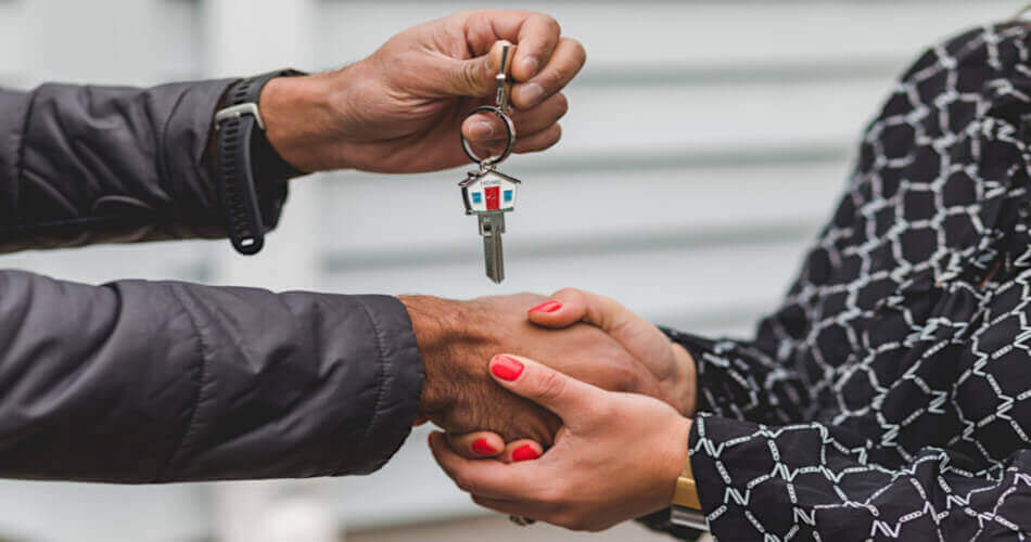 A seller or agent's hand places new home keys into the hands of a buyer