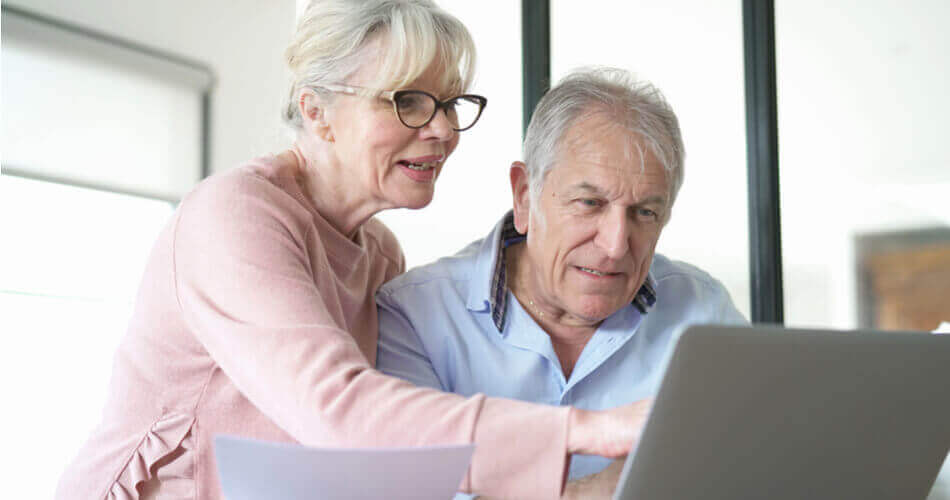 Elderly couple looking and gesturing towards a computer screen
