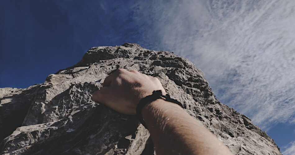 Hand of climber ascending cliff face, symbolizing climb up from poverty