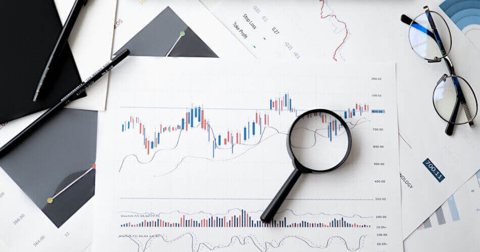 Stock price chart, magnifying glass, and other documents for performing due diligence on potential investments
