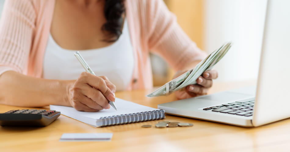 Woman holding money and writing in a notebook, calculating how much $39/hour a year would equal