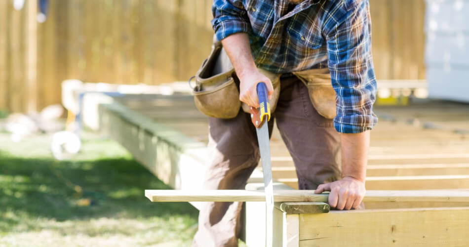 Construction worker sawing wood to build a shed