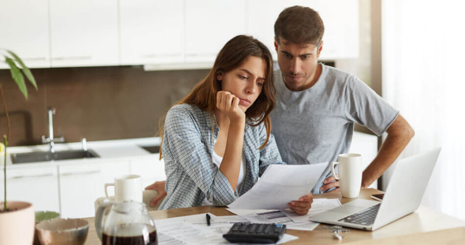 Couple looking at their budget on a laptop and deciding between payday loans vs. personal loans for emergency expenses
