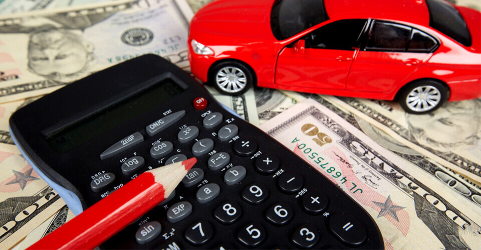 Pile of money with red toy car and calculator on top