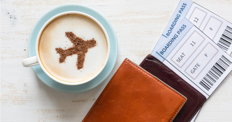 Coffee cup with airplane design next to wallets and airline tickets
