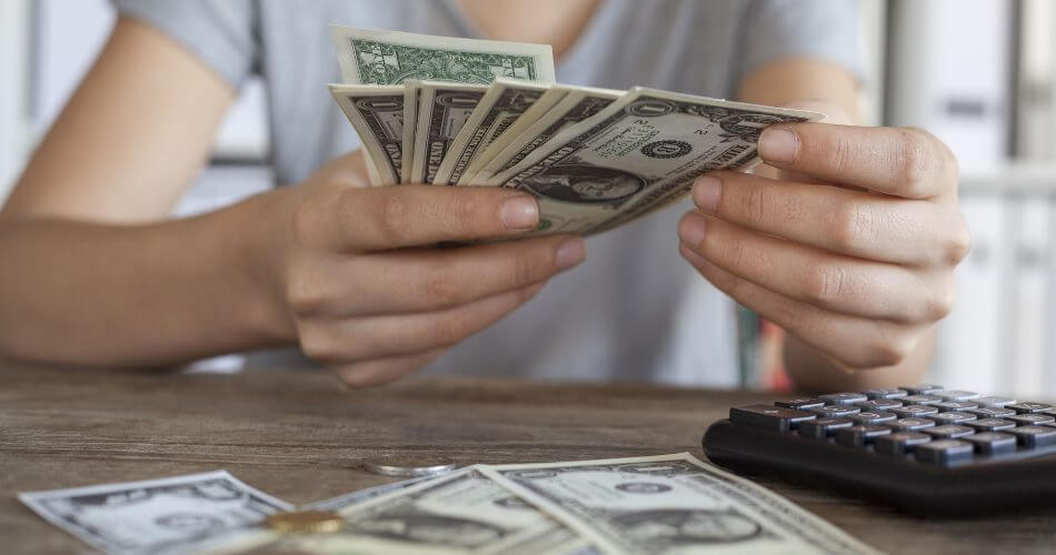 Hands counting $100 bills, calculating how much $86/hour a year would equal