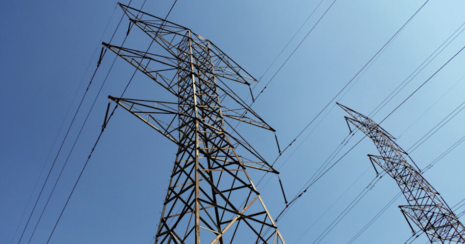 view of electrical power lines against a blue sky, seen from below