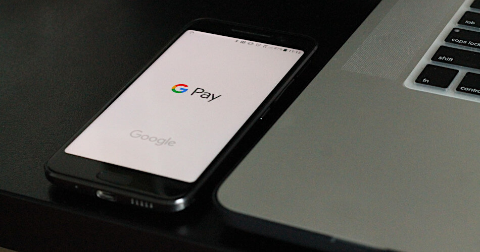 Google Pay app displayed on phone next to laptop