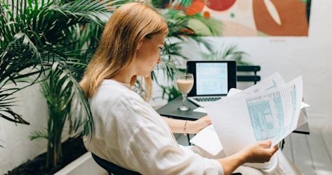 women reviews printed tax forms with return she is preparing online blurred in the background