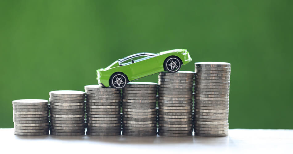 Green model car on a stack of coins, representing the market before used car prices drop