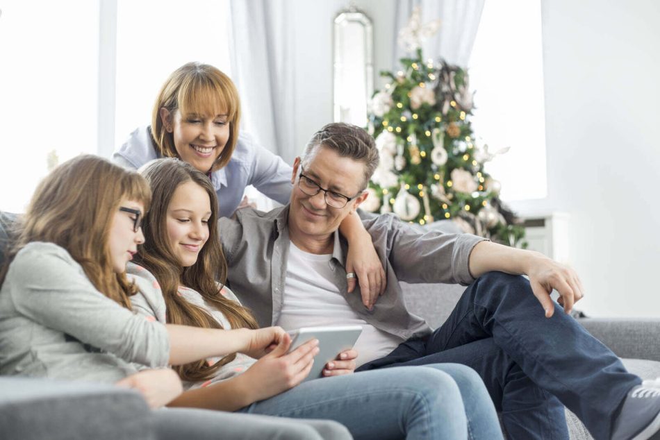 Family sitting on couch with a Christmas tree in the background