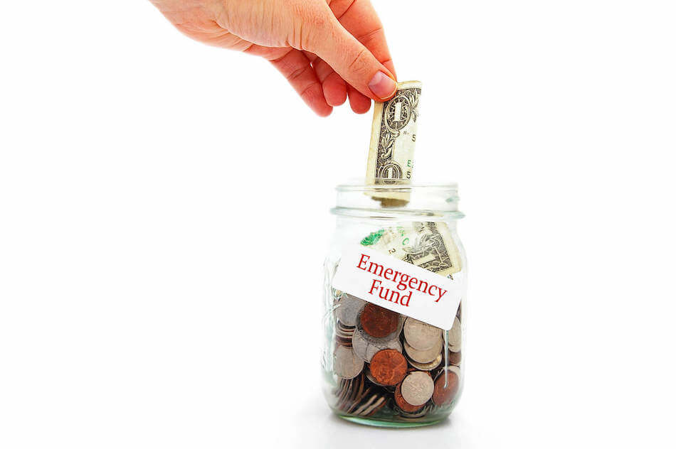 Hand putting money into an Emergency Fund jar