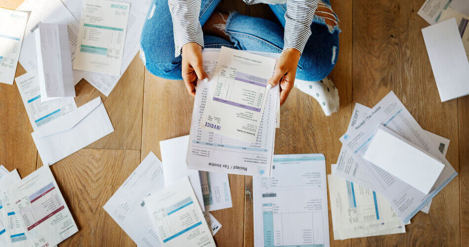 Person sitting cross legged surrounded by tax documents for the IRS hardship program