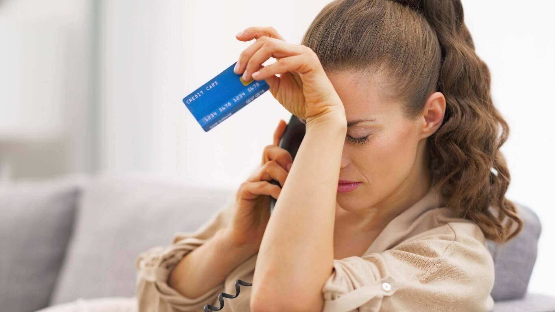 Woman holding a credit card looking stressed as she learns she was charged an overdraft fee because she didn't have overdraft protection