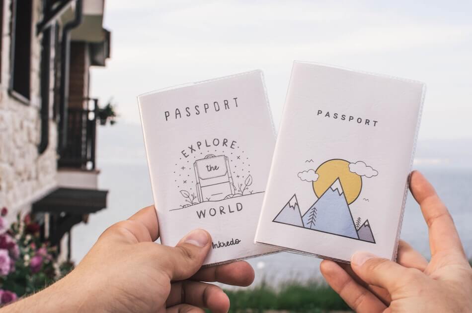 Hands holding up two passports with illustrations on them