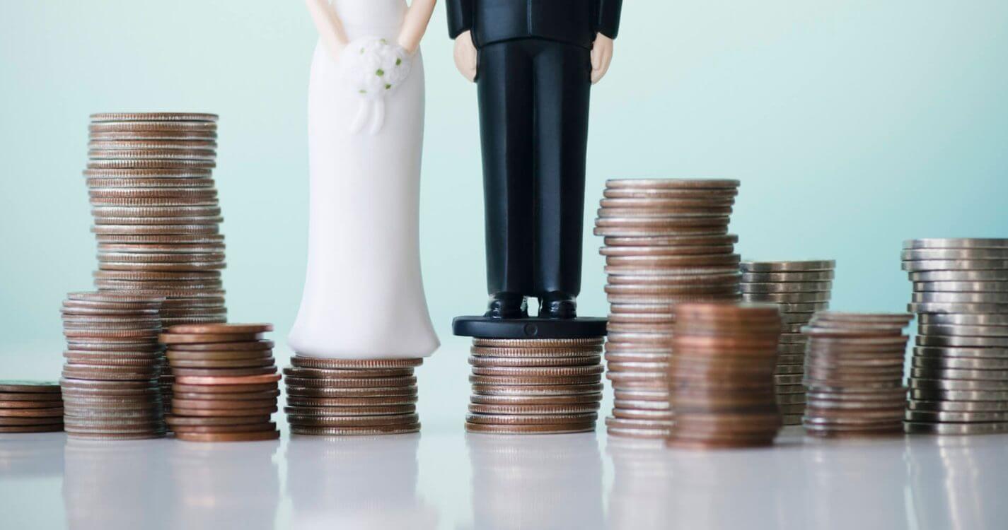 Bride and groom figures on stacks of coins, representing the average cost of a wedding dress