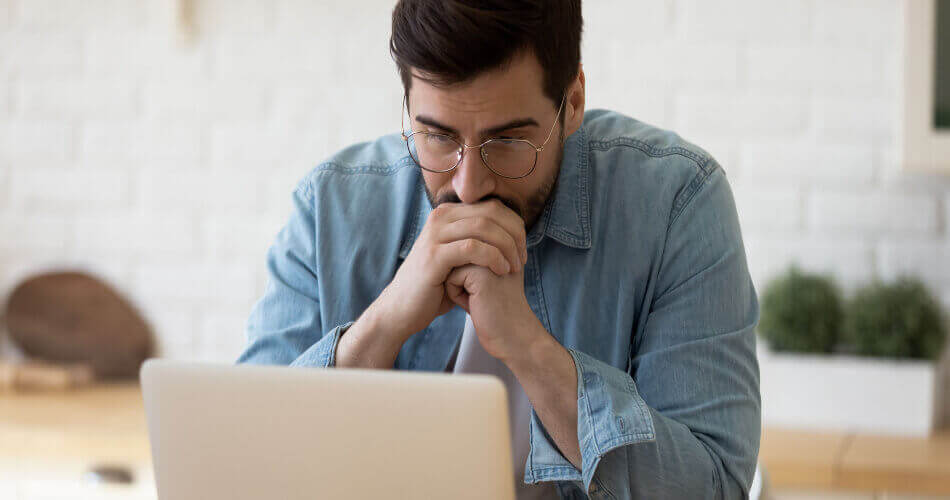 Man looking pensively at a laptop screen