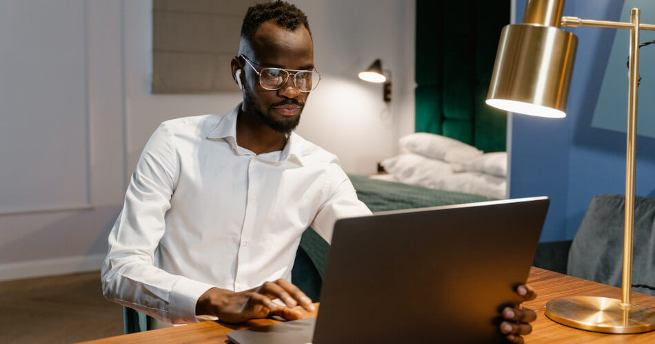 A man with glasses at a laptop, clearly focused and thoughtful. Perhaps he is closing on home purchase.